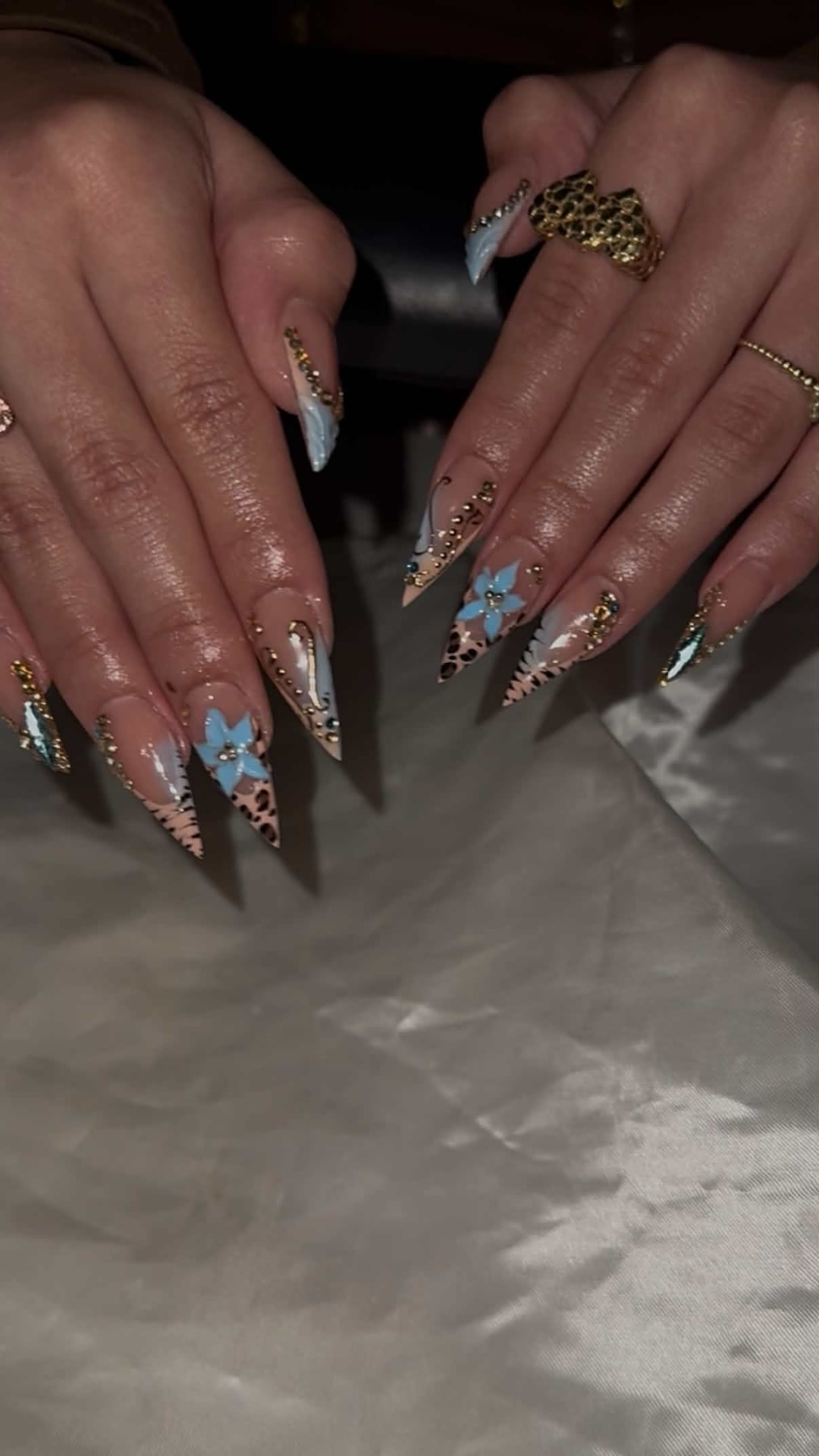 Long stiletto nails with leopard print, blue flowers and gold charms